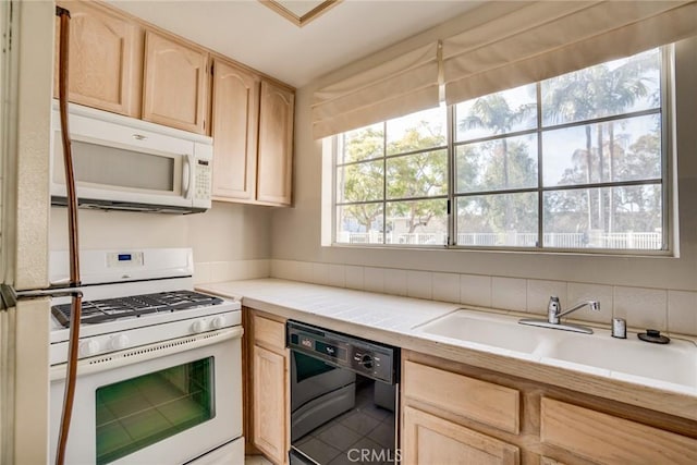 kitchen featuring sink, white appliances, light brown cabinetry, and tile counters