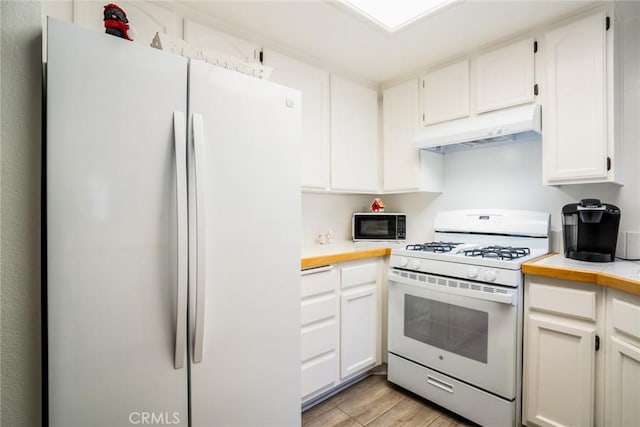 kitchen with white cabinets, light wood-type flooring, white appliances, and tile countertops