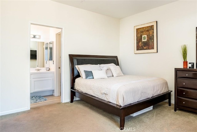 bedroom featuring ensuite bathroom and light colored carpet