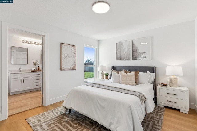 bedroom featuring sink, connected bathroom, and light hardwood / wood-style floors