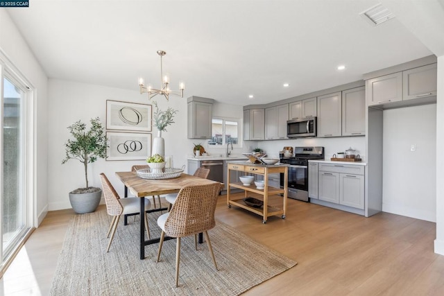 dining room with sink, an inviting chandelier, and light hardwood / wood-style flooring