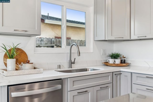 kitchen featuring sink, gray cabinetry, dishwasher, and light stone counters