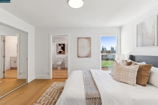 bedroom with a closet, wood-type flooring, and ensuite bath