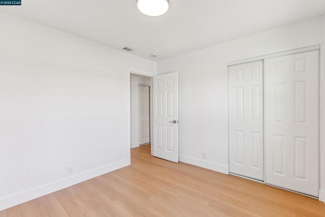 unfurnished bedroom with a closet and light hardwood / wood-style floors