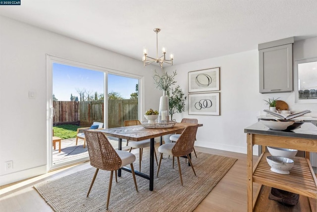 dining area with light hardwood / wood-style flooring and an inviting chandelier