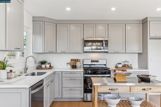 kitchen with light stone countertops, sink, appliances with stainless steel finishes, and gray cabinets