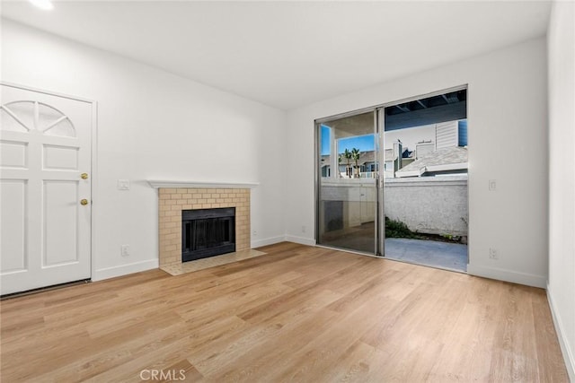 unfurnished living room featuring a brick fireplace and wood-type flooring