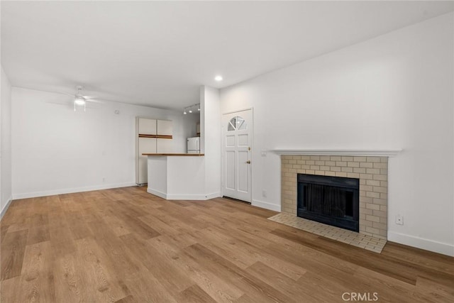 unfurnished living room with ceiling fan, light hardwood / wood-style flooring, and a fireplace