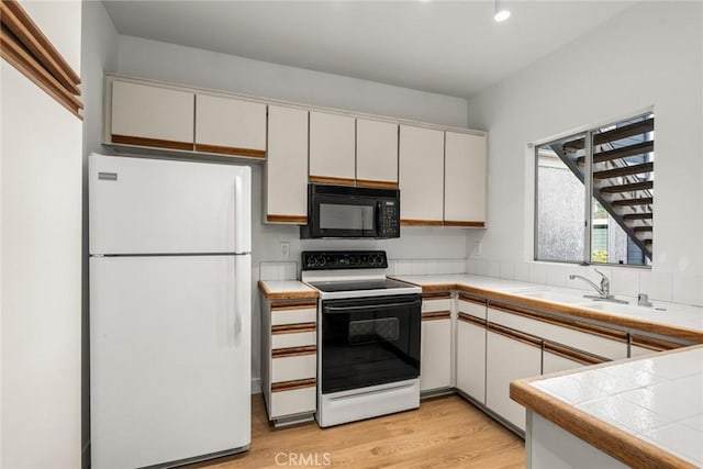 kitchen featuring white refrigerator, white cabinets, and electric stove