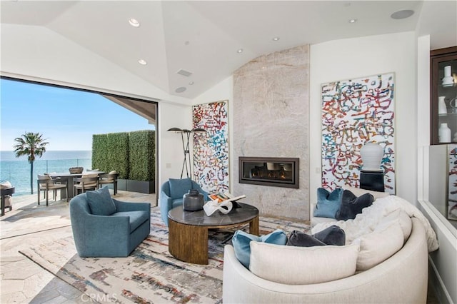 living room with a water view, vaulted ceiling, and a high end fireplace