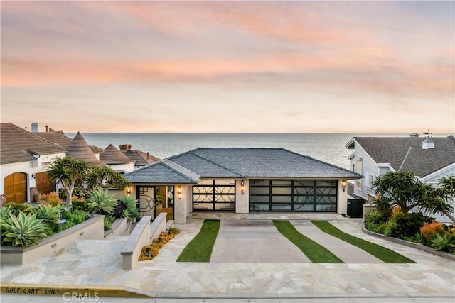 view of front facade featuring a water view, central AC unit, and a garage