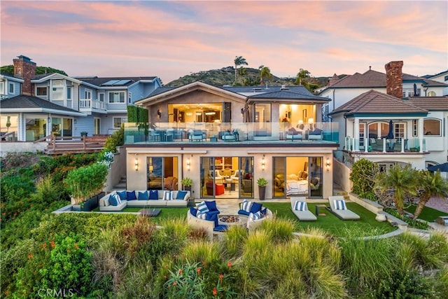 back house at dusk featuring an outdoor living space with a fire pit