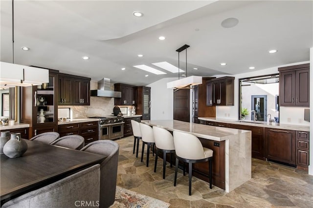 kitchen with decorative light fixtures, a center island, a breakfast bar, vaulted ceiling with skylight, and double oven range