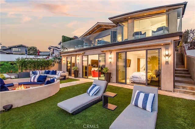 back house at dusk featuring a patio, a yard, and an outdoor living space with a fire pit