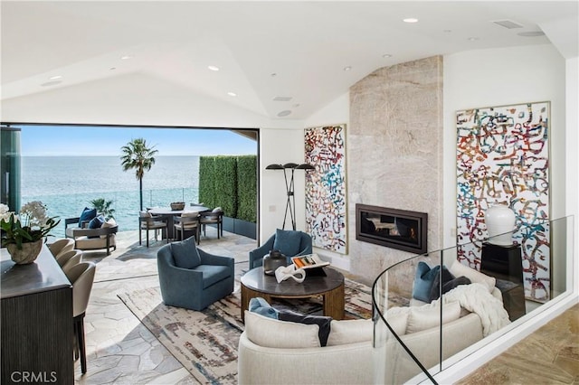 living room with a premium fireplace, a water view, and vaulted ceiling