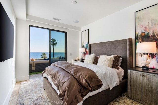 bedroom with access to exterior, a water view, and light hardwood / wood-style flooring