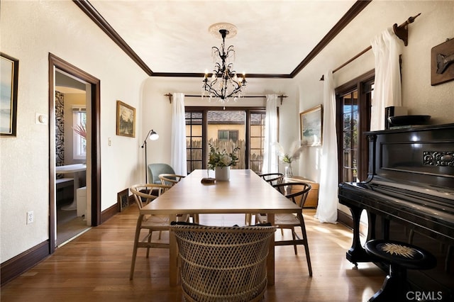 dining area featuring crown molding, hardwood / wood-style floors, and an inviting chandelier