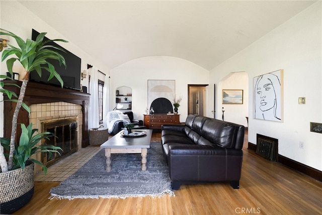 living room with brick ceiling, wood-type flooring, a fireplace, and vaulted ceiling