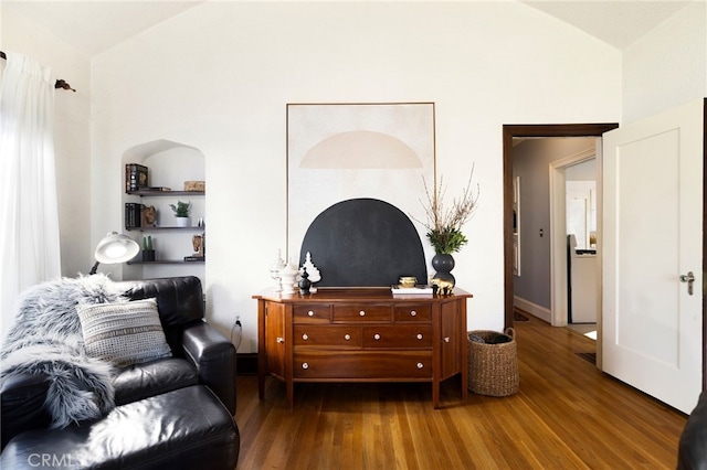 sitting room featuring built in shelves, lofted ceiling, and dark wood-type flooring