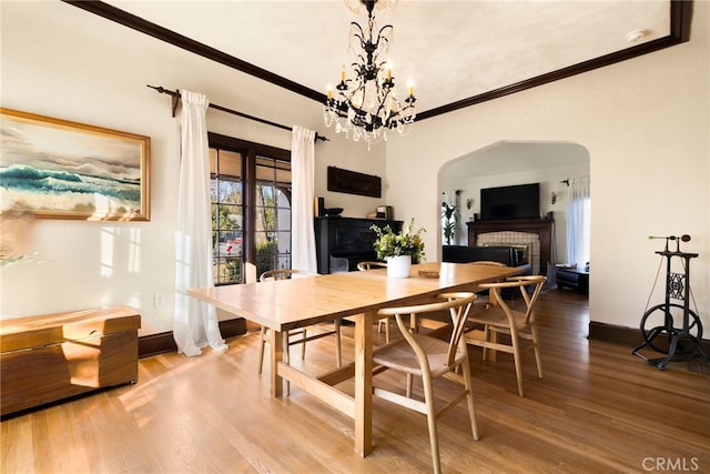 dining room with hardwood / wood-style flooring, ornamental molding, and an inviting chandelier