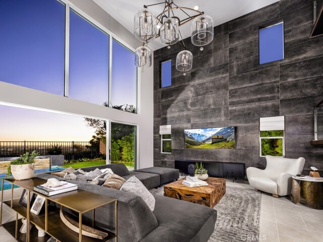 living room with a chandelier, a towering ceiling, and tile patterned flooring