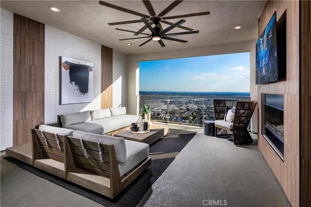 living room with a textured ceiling, ceiling fan, and a large fireplace