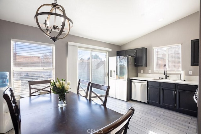 dining space with sink, a chandelier, and lofted ceiling