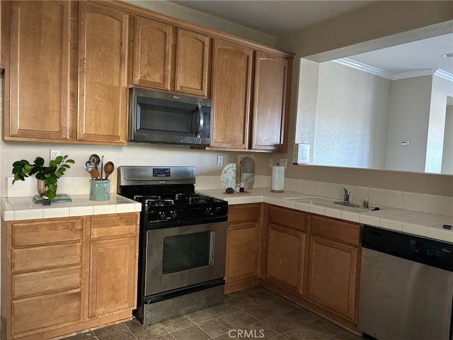 kitchen with sink, ornamental molding, tile countertops, and stainless steel appliances