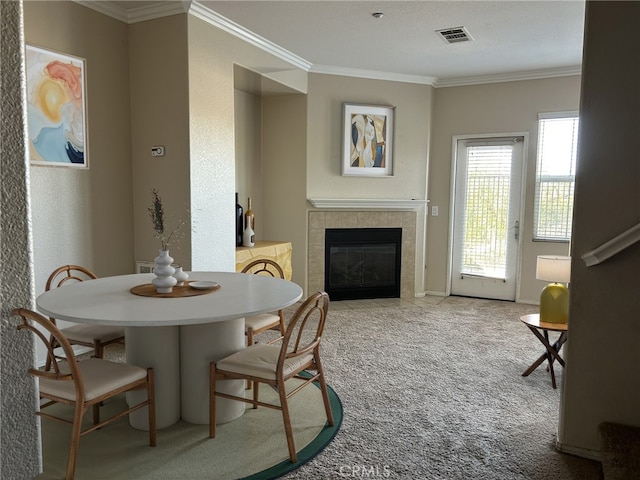 carpeted dining space featuring a tiled fireplace and ornamental molding