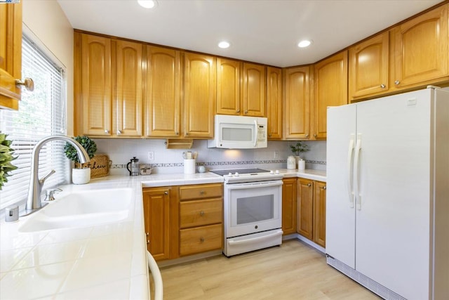 kitchen featuring white appliances, decorative backsplash, sink, tile countertops, and light wood-type flooring