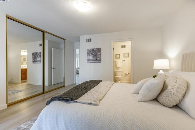 bedroom with hardwood / wood-style floors, a closet, and ensuite bathroom