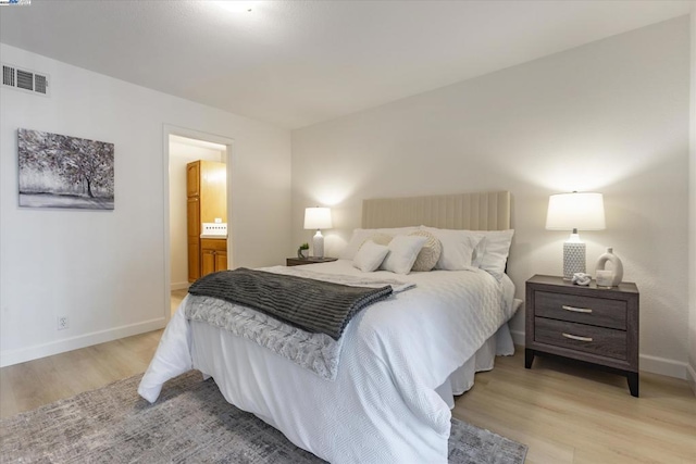 bedroom featuring connected bathroom and light hardwood / wood-style flooring