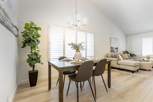 dining space with light wood-type flooring, high vaulted ceiling, and a notable chandelier