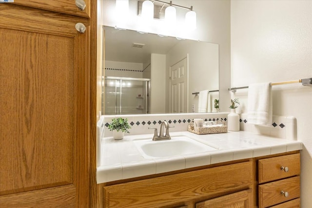 bathroom featuring a shower with shower door and vanity