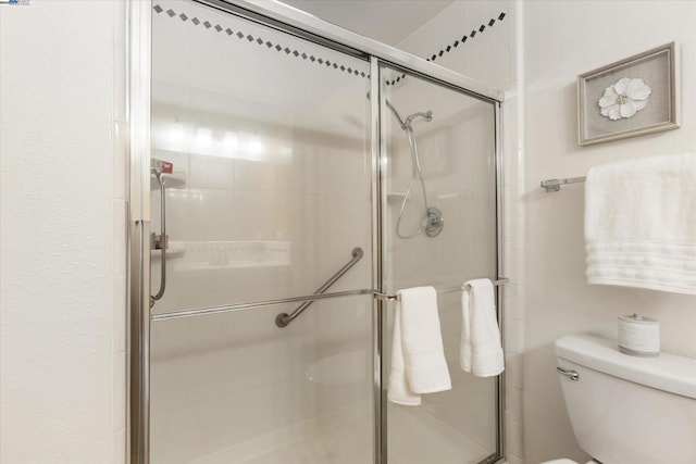 bathroom featuring toilet and a shower with door