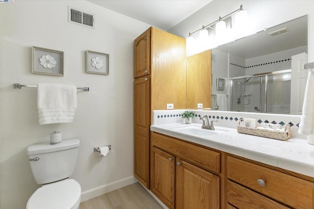 bathroom featuring wood-type flooring, tasteful backsplash, toilet, walk in shower, and vanity