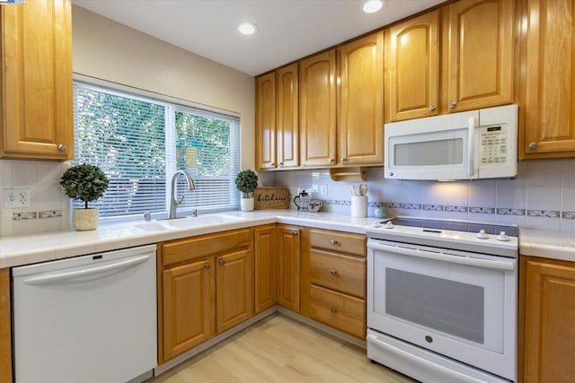 kitchen featuring sink, white appliances, light hardwood / wood-style flooring, and tasteful backsplash