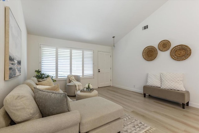 living room with high vaulted ceiling and light hardwood / wood-style flooring