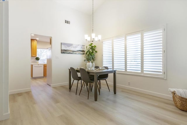 dining space with light wood-type flooring, a chandelier, and high vaulted ceiling