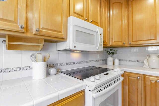 kitchen featuring white appliances, tile counters, and tasteful backsplash