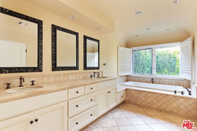 bathroom featuring tile patterned floors, a relaxing tiled tub, and vanity