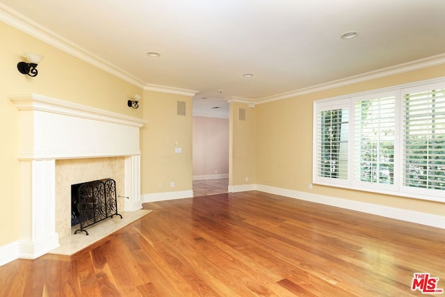 unfurnished living room featuring wood-type flooring, a fireplace, and ornamental molding