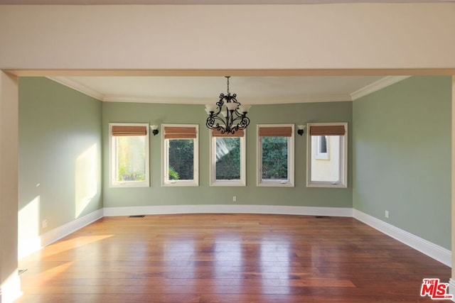 empty room featuring hardwood / wood-style floors, crown molding, and a notable chandelier