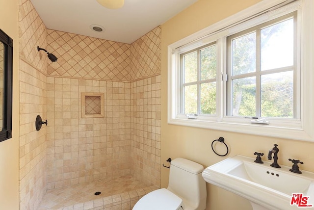 bathroom with sink, toilet, and a tile shower