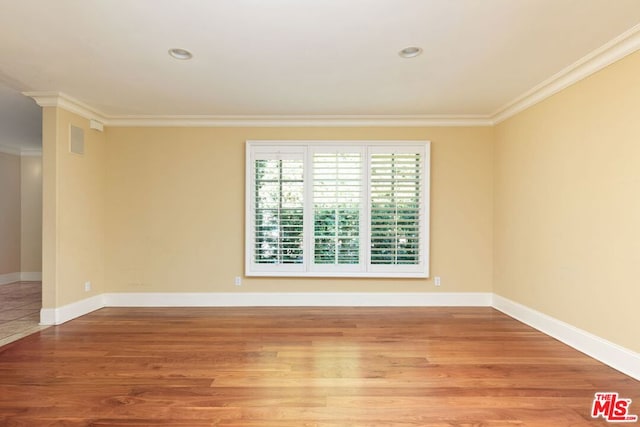 spare room featuring crown molding and light wood-type flooring