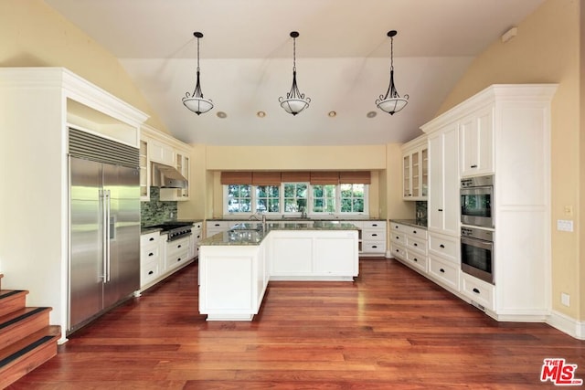 kitchen featuring light stone countertops, white cabinetry, stainless steel appliances, backsplash, and vaulted ceiling