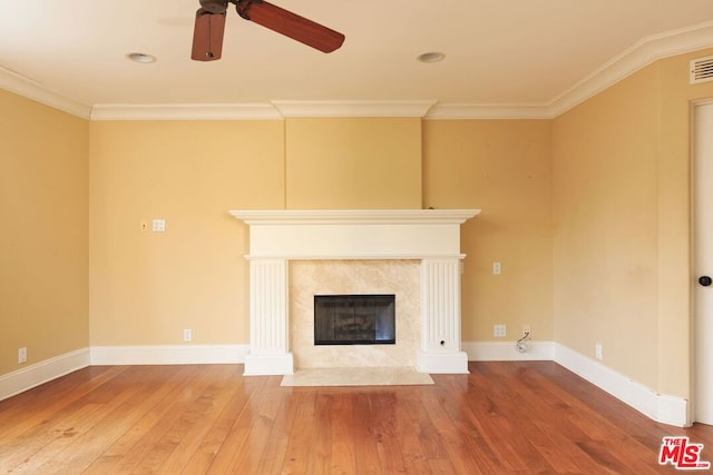 unfurnished living room featuring ceiling fan, hardwood / wood-style floors, a high end fireplace, and ornamental molding