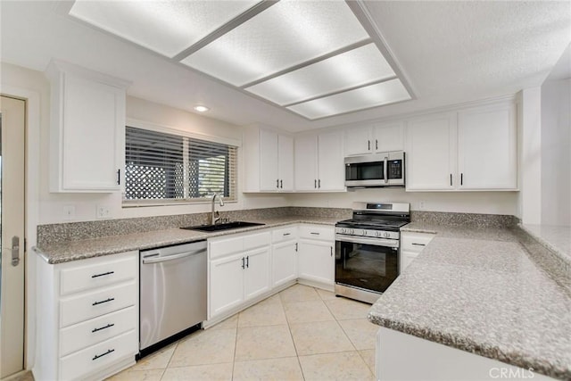 kitchen with sink, white cabinets, light tile patterned floors, and appliances with stainless steel finishes