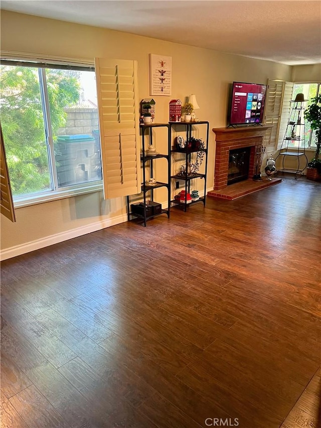 living room featuring a brick fireplace and dark wood-type flooring