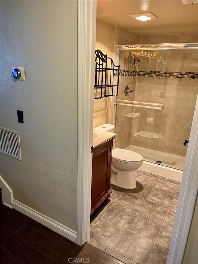 bathroom with toilet, a shower with door, and vanity